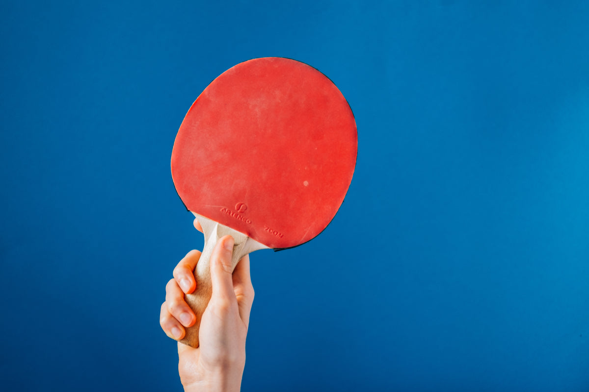 hand holding ping pong paddle on blue background
