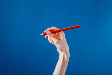 hand holding red colored pencil on blue background