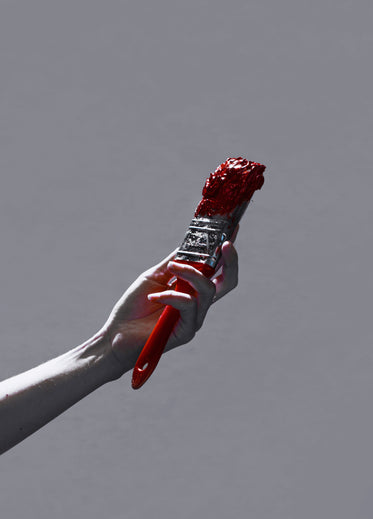 hand holding up red paint brush