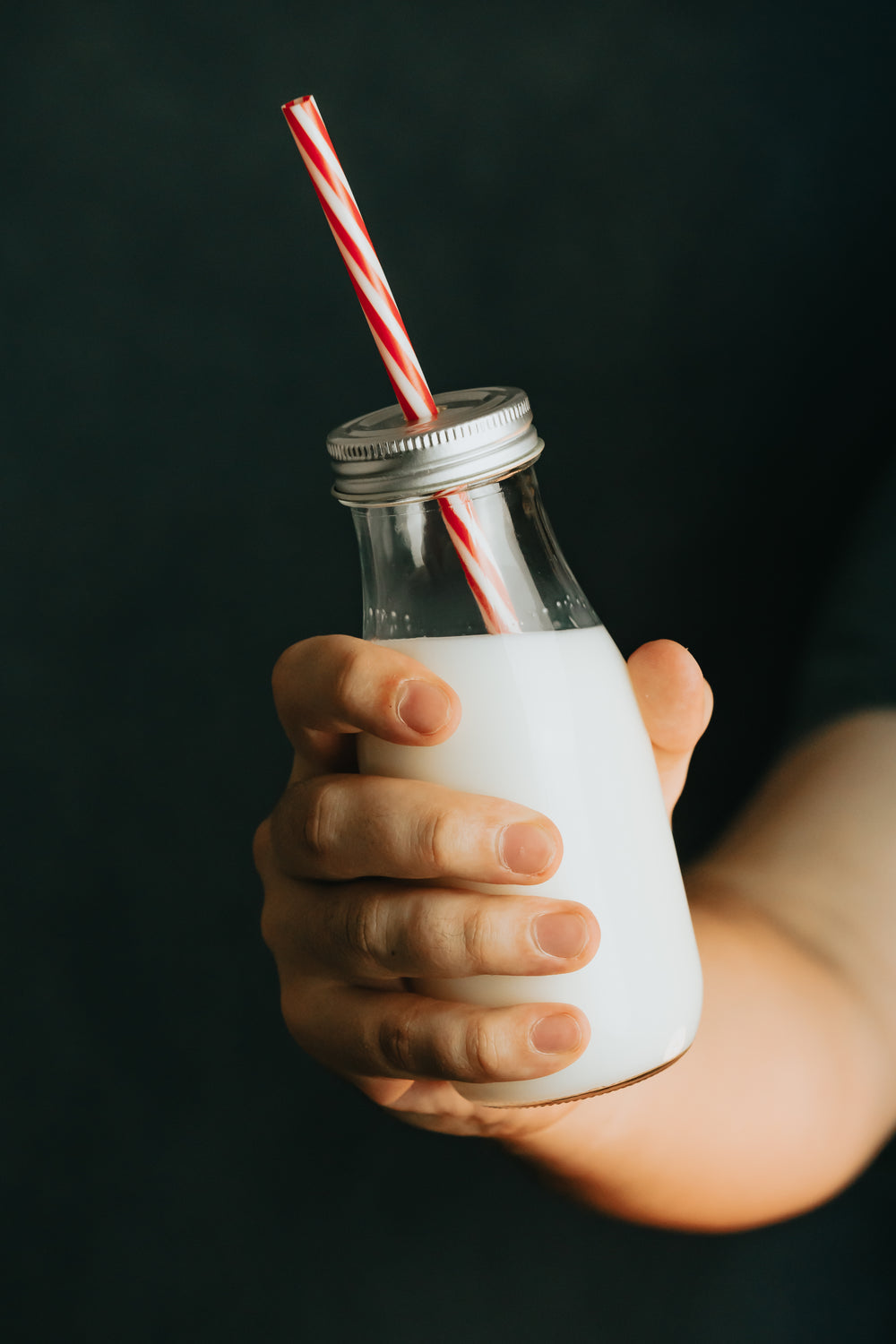 hand holds a glass bottle of milk