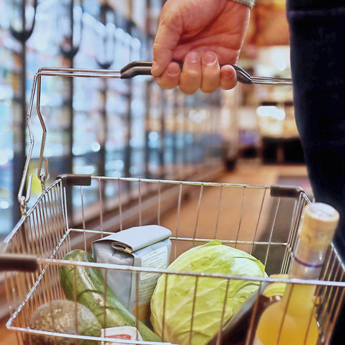 hand holds a shopping basket with fresh vegetables