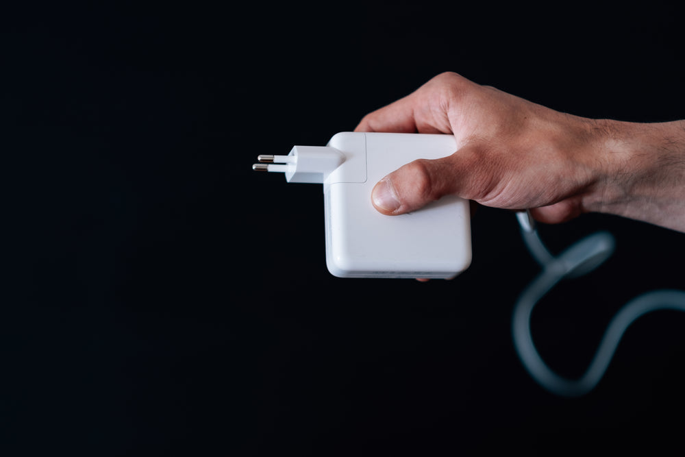hand holds a square charger against a black background