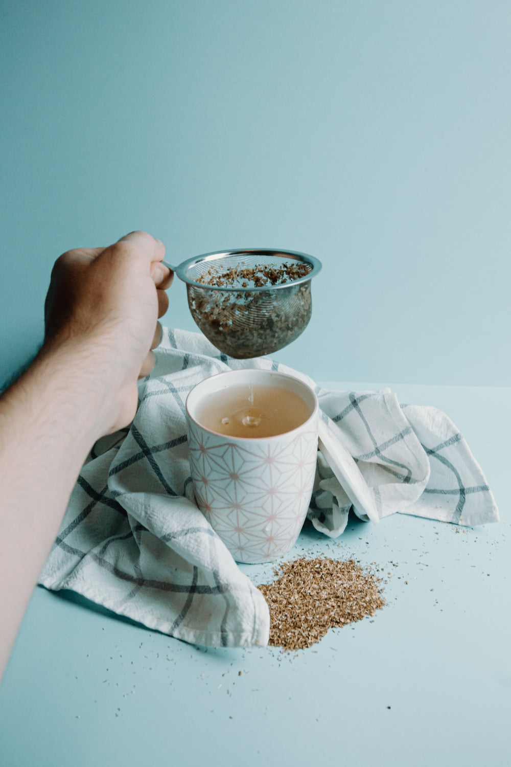 hand holds a stainer from a cup of tea