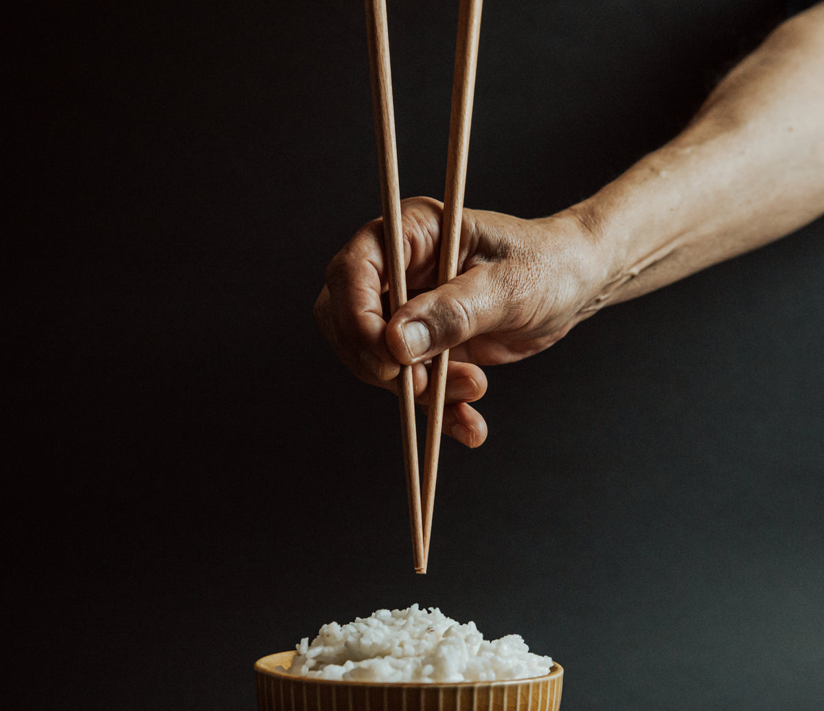hand holds chopsticks over a bowl of rice