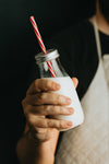 hand holds clear bottle of milk with a straw