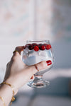 hand holds glass full of water topped with cranberries