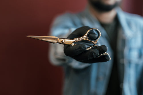 hand holds out elegant gold scissors