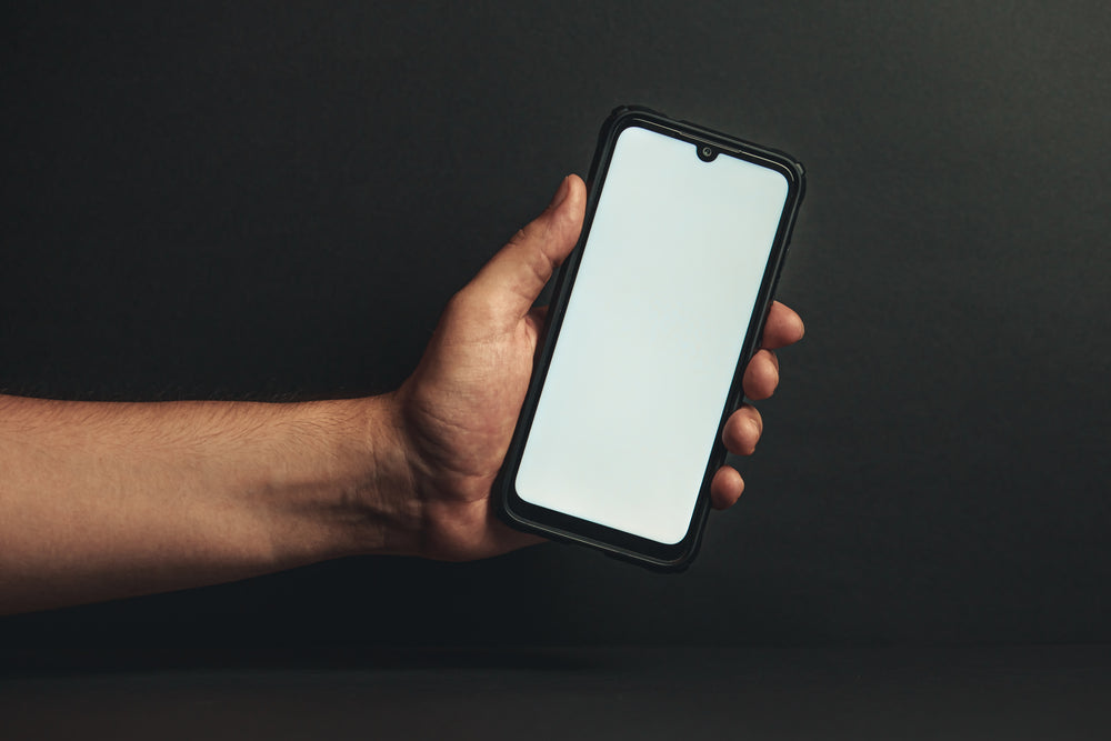 hand holds out phone against black background