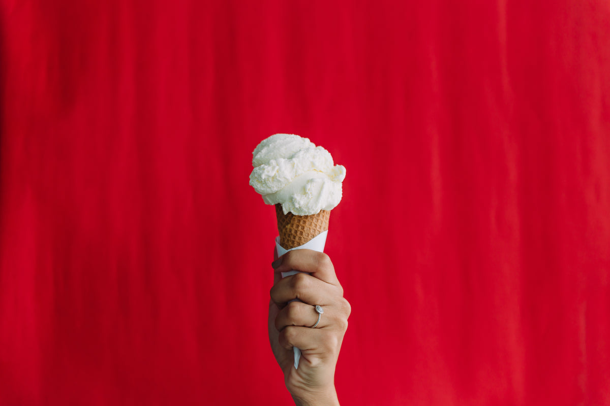 手在红色的背景下举着一个冰淇淋蛋筒