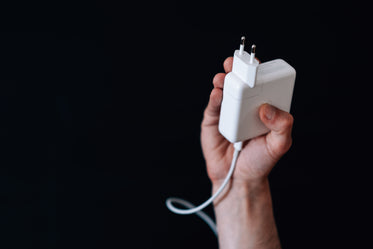 hand holds up a white square computer charger