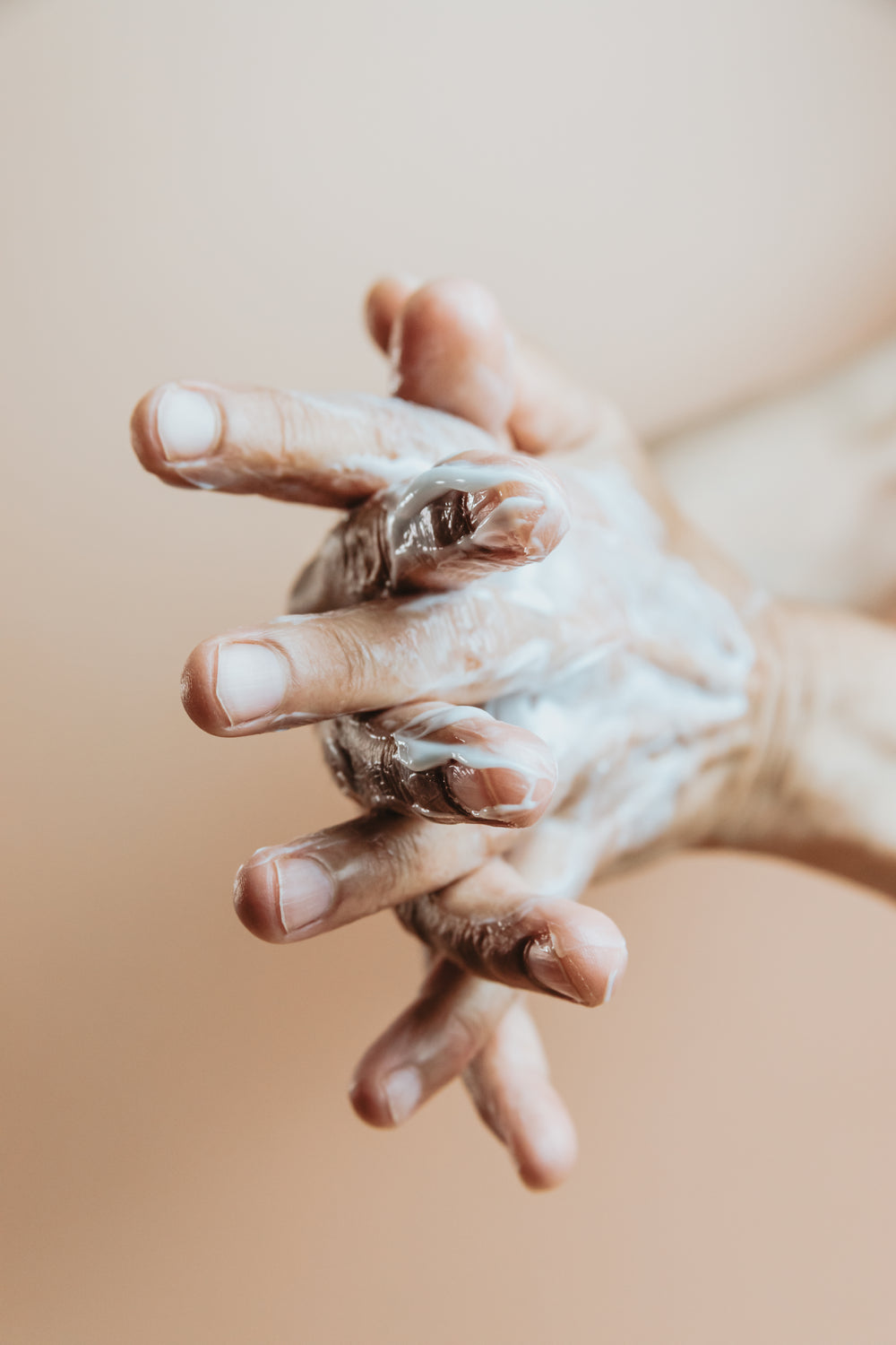 hand lather lotion on in front of a beige background