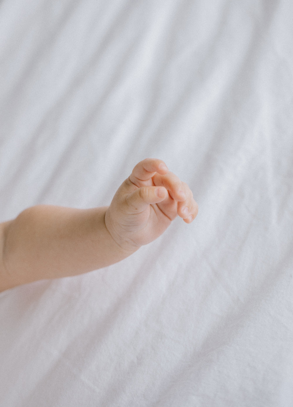 hand of newborn baby against white fabric