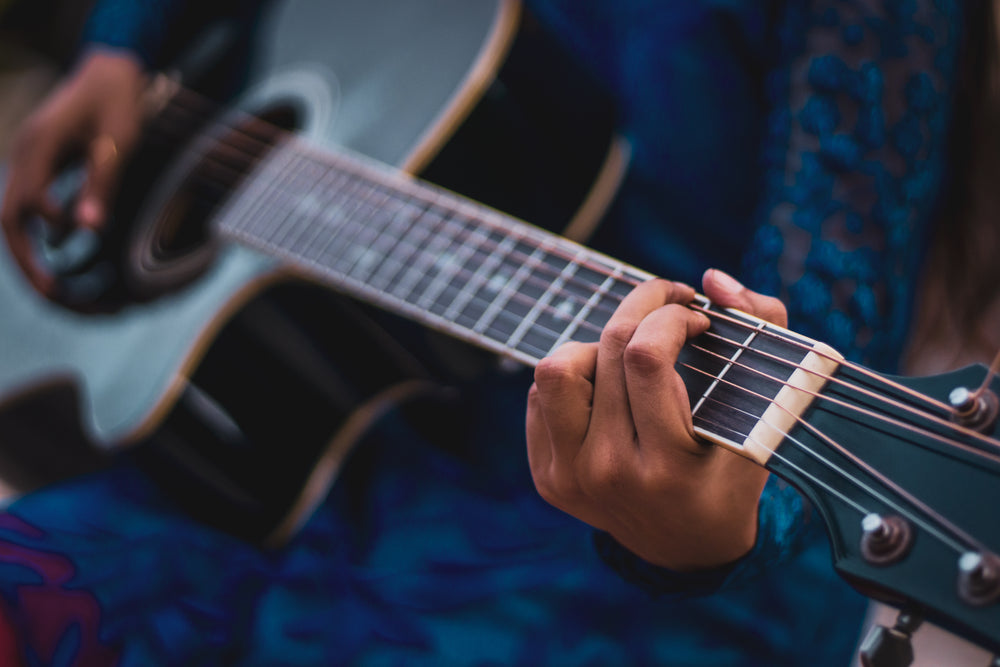 hand on the neck of a guitar in a g chord