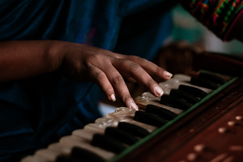 hand placed on the iridescent keys of a small piano