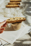 hand places biscotti cookie over a cup of coffee