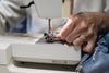 hand runs denim through sewing machine