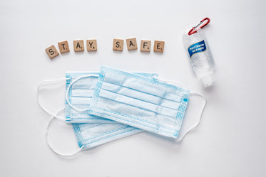 hand sanitizer, face masks and letter tiles spelling safe hands