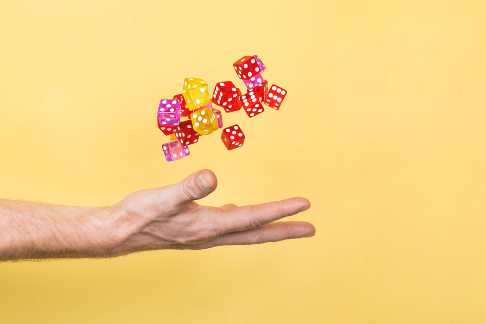 hand throwing dice on yellow