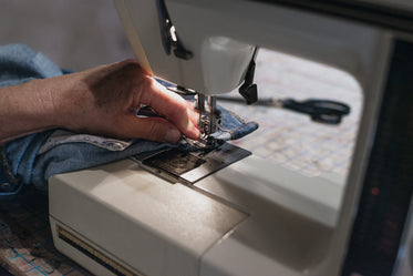 hand uses sewing machine on denim