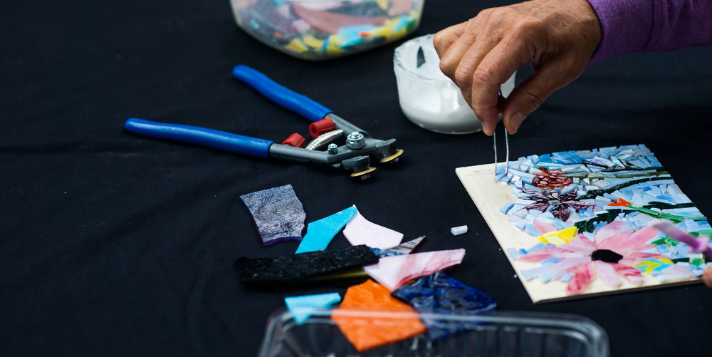 hand uses tweezers to add to a mosaic