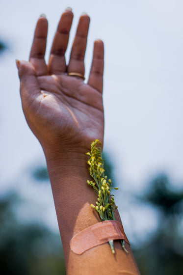 hand with an adhesive bandage reaches towards the sky