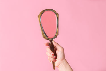 hand with painted nails holds up a mirror