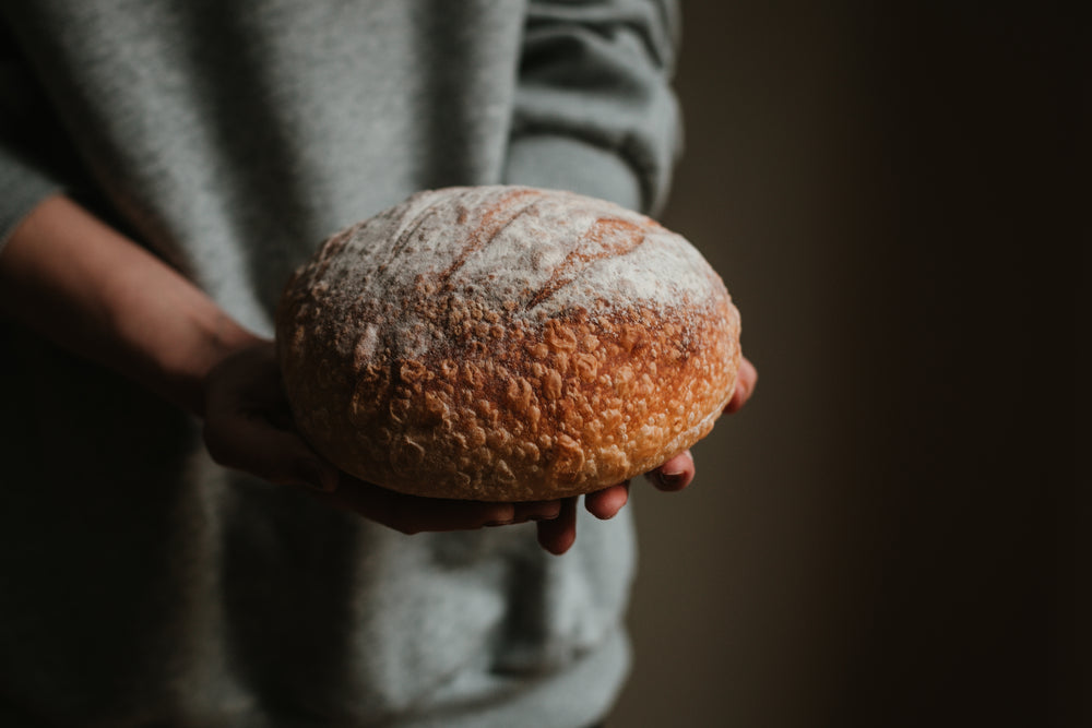 hands cradle fresh sourdough bread