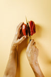 hands cut a red pepper with a sharp knife
