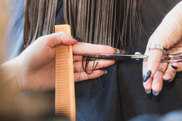 hands cutting long brown hair