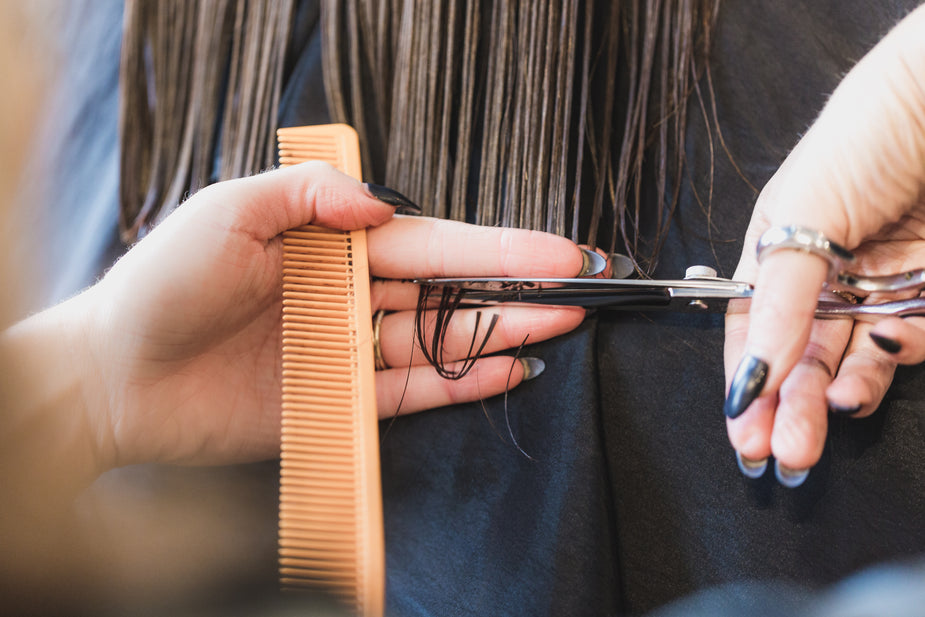 Woman receiving a hair trim to keep hair healthy and long | Mane Addicts