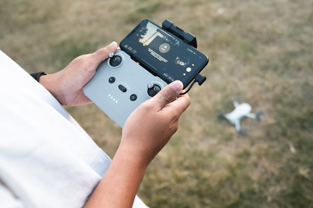 hands grasp the controls of a drone outdoors