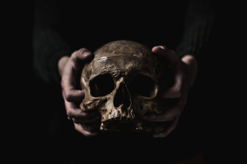 hands grip a human skull