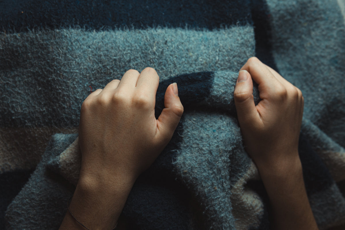 hands grip a thick wool blanket