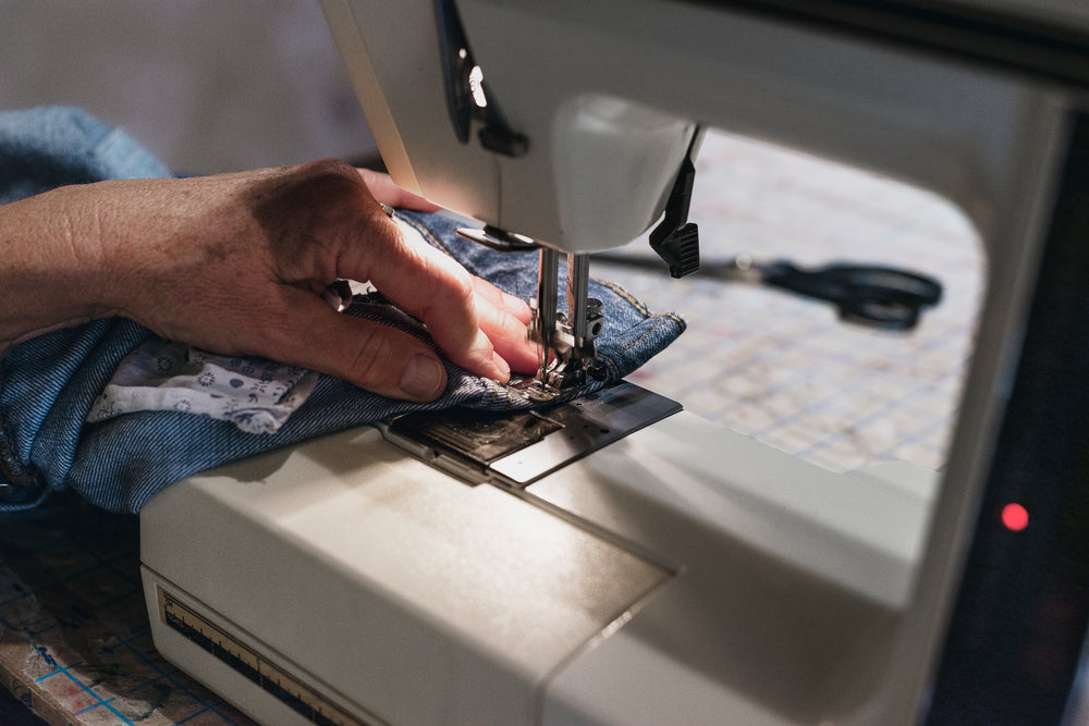 hands guiding demin on sewing machine