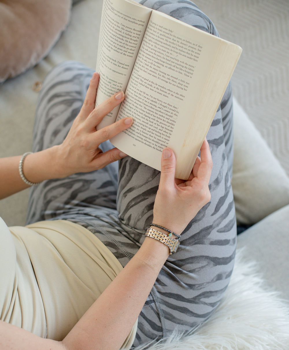 hands hold a book over striped pants