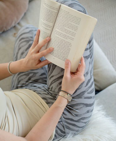 hands hold a book over striped pants