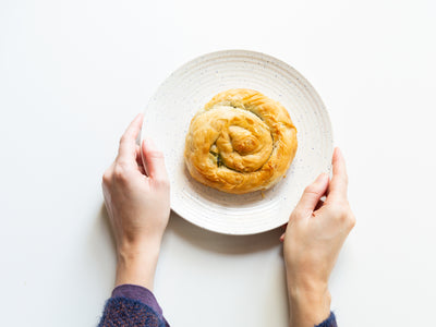 Hands Hold A Plate of Spanakopita