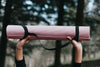 hands hold up a pink yoga mat outdoors
