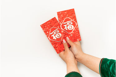 hands hold up two red cards against a white background