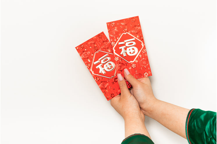 Hands Hold Up Two Red Cards Against A White Background