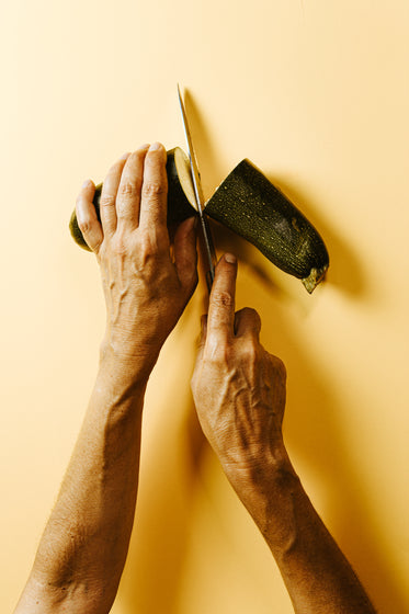 hands holding and cutting a zucchini