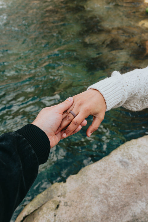 hands holding each other above blue clear water