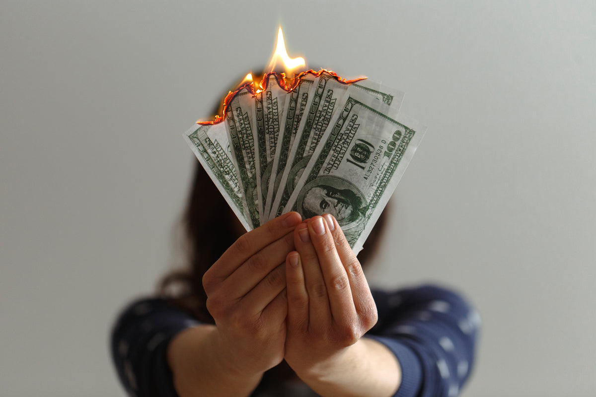 hands holding money aflame