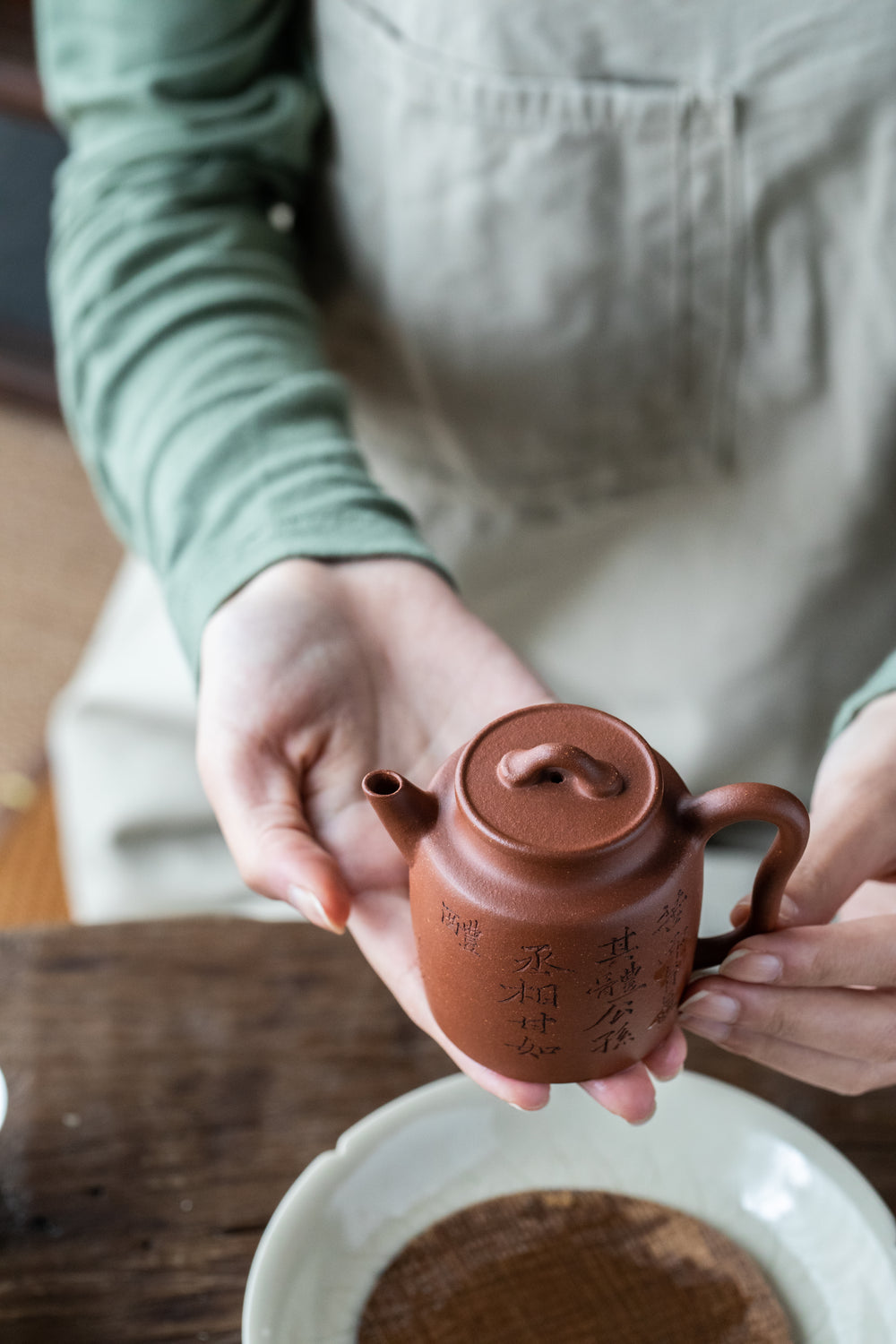 hands holding up a chinese ceramic teapot