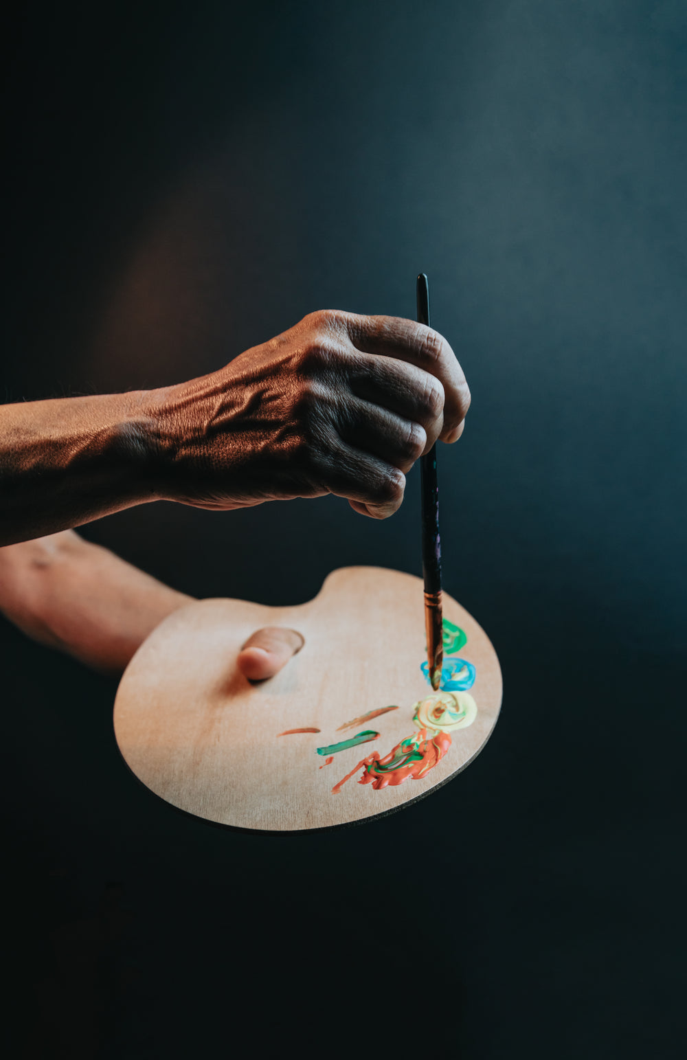 hands holds a paint brush to a wooden pallet