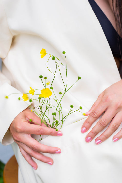 hands holds buttercup flowers in the pocket of their coat