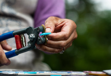 hands holds glass cutters trimming blue glass