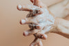 hands lathered in hand cream against beige background