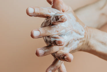 hands lathered in hand cream against beige background