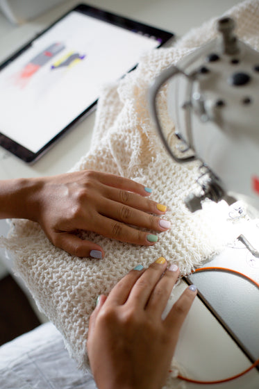 hands line up fabric into a sewing machine